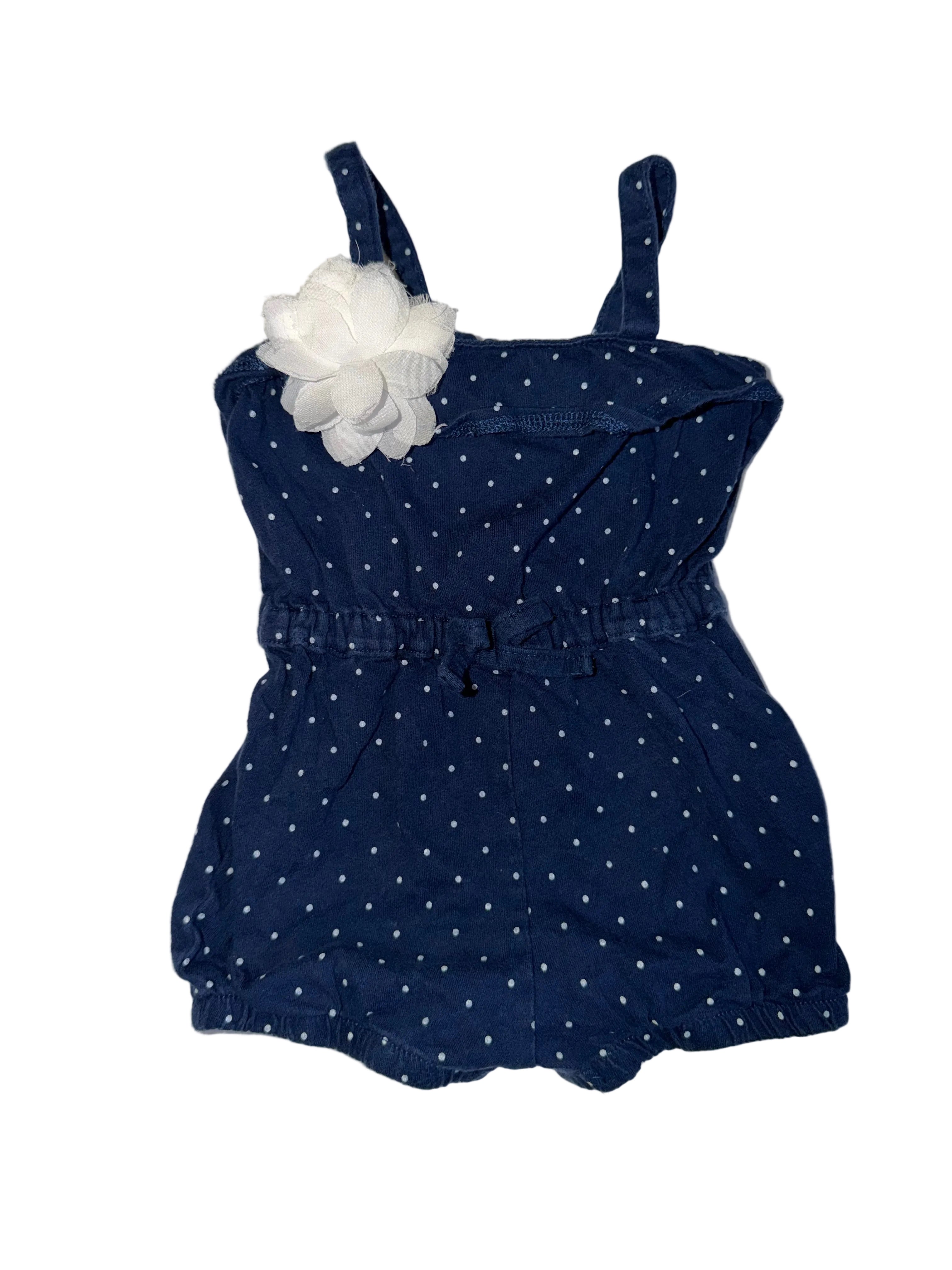Navy blue polka dot romper with white headband on a white surface